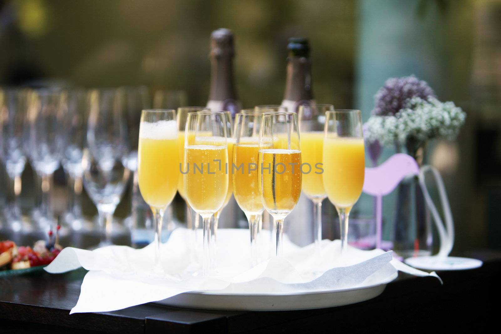 Flutes of champagne and orange juice for toasting speeches at a celebration on a tray on a buffet table 