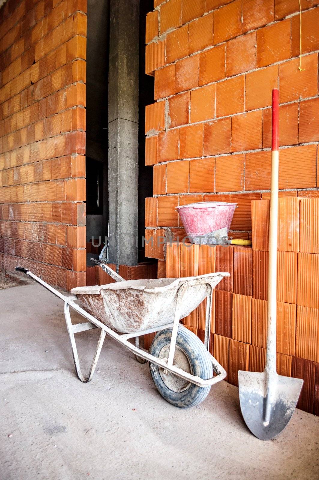 Brick Mason's Wheelbarrow on construction sit with shovel and bucket.