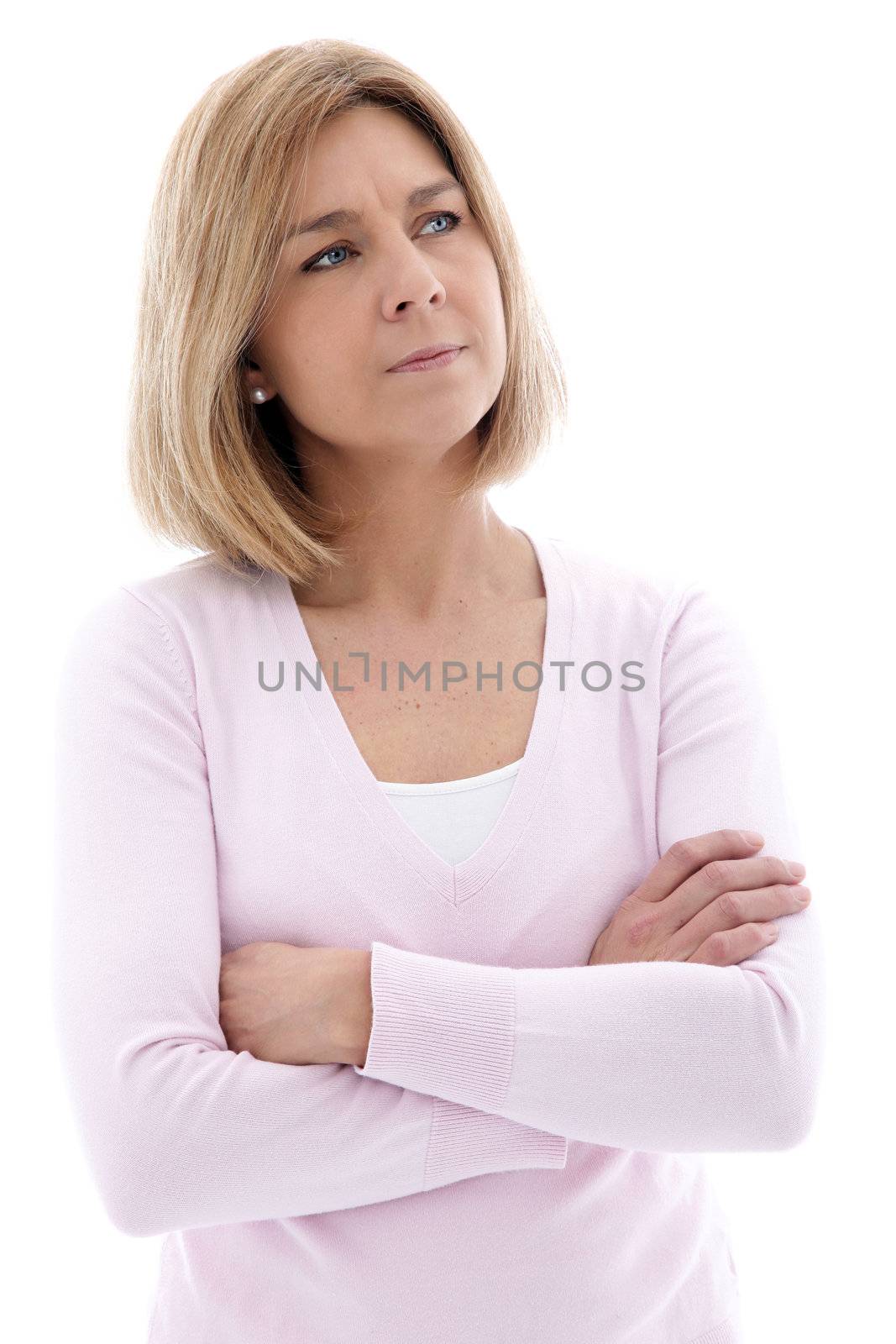 Pensive middle aged blond woman standing with folded arms staring up into the air with a frown, isolated on white