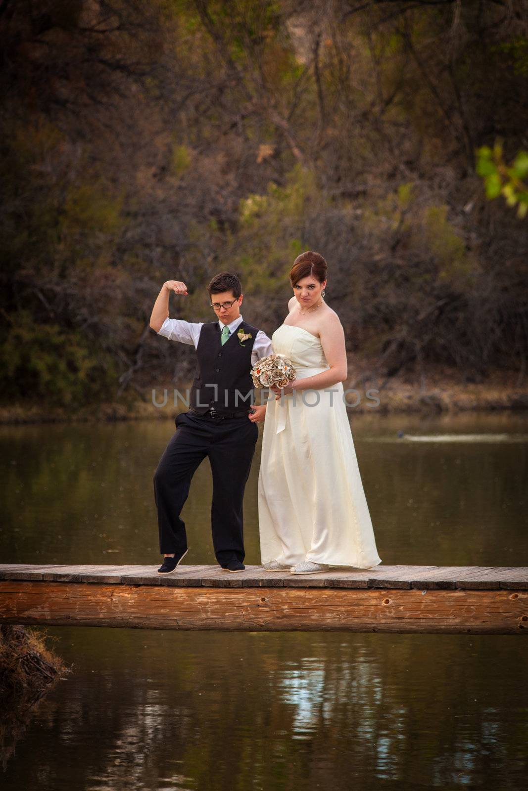 Macho lesbian groom with bride on dock over pond