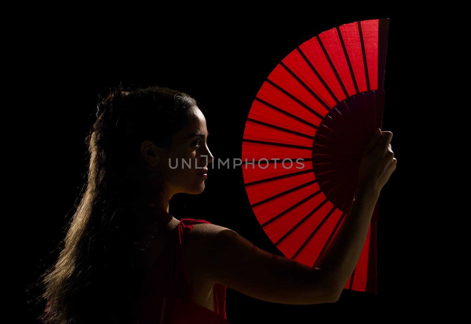 Female dancer holding a backlit red folding fan