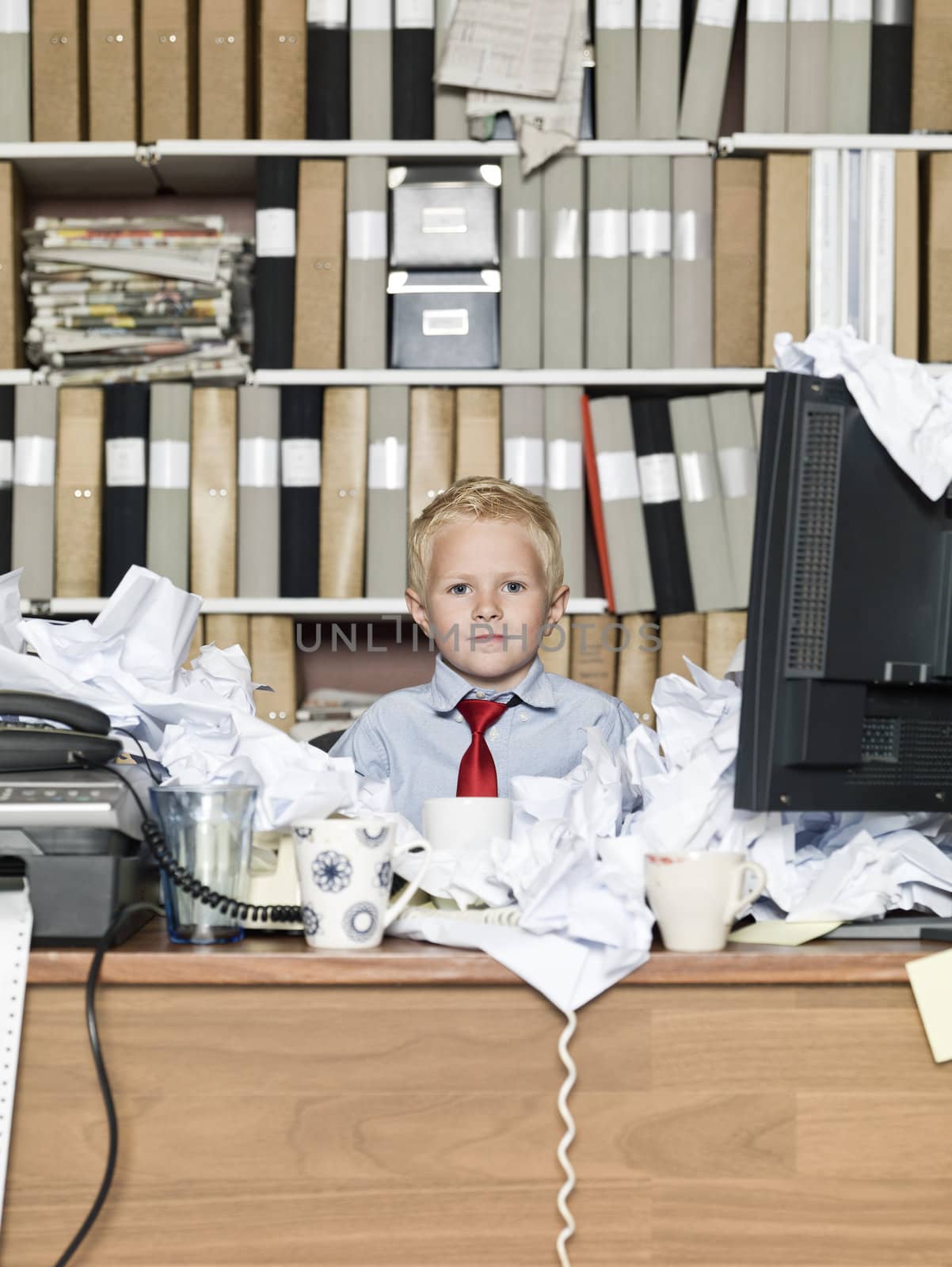 Young boy as a business man in a messy office
