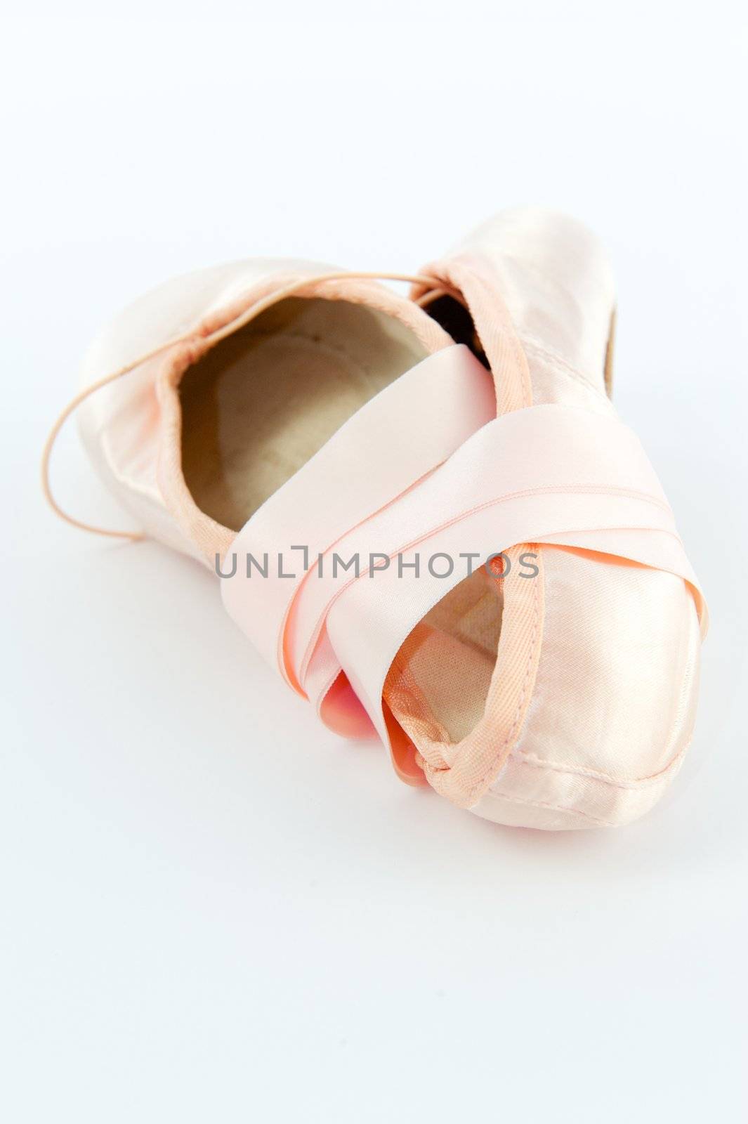 A pair light or pale pink ballet point shoes or slippers isolated on a white background with a lot of copyspace