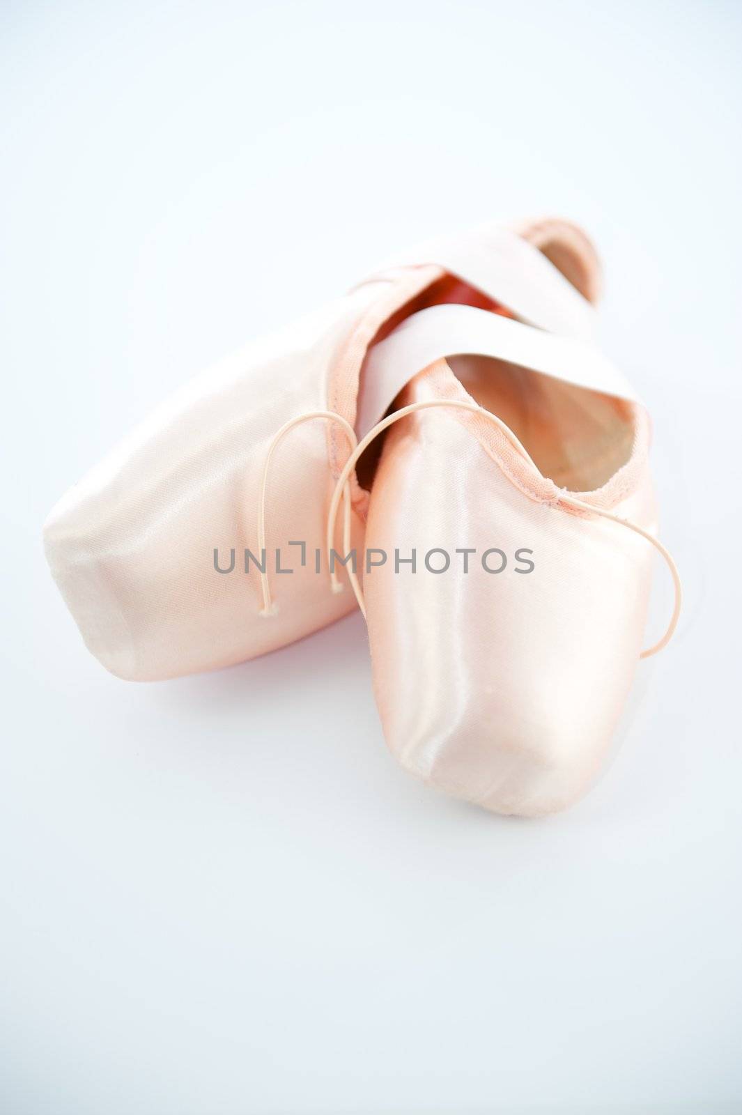 A pair light or pale pink ballet point shoes or slippers isolated on a white background with a lot of copyspace