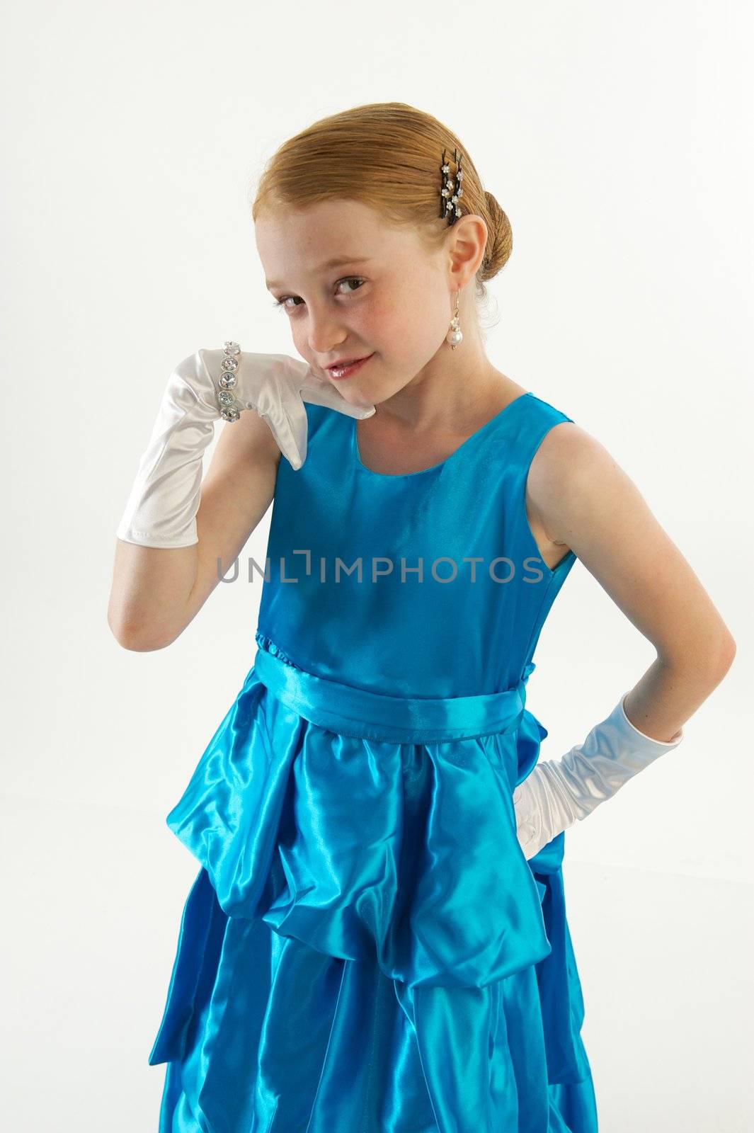 A young redheaded little girl in a blue ball gown with white gloves and jewelry
