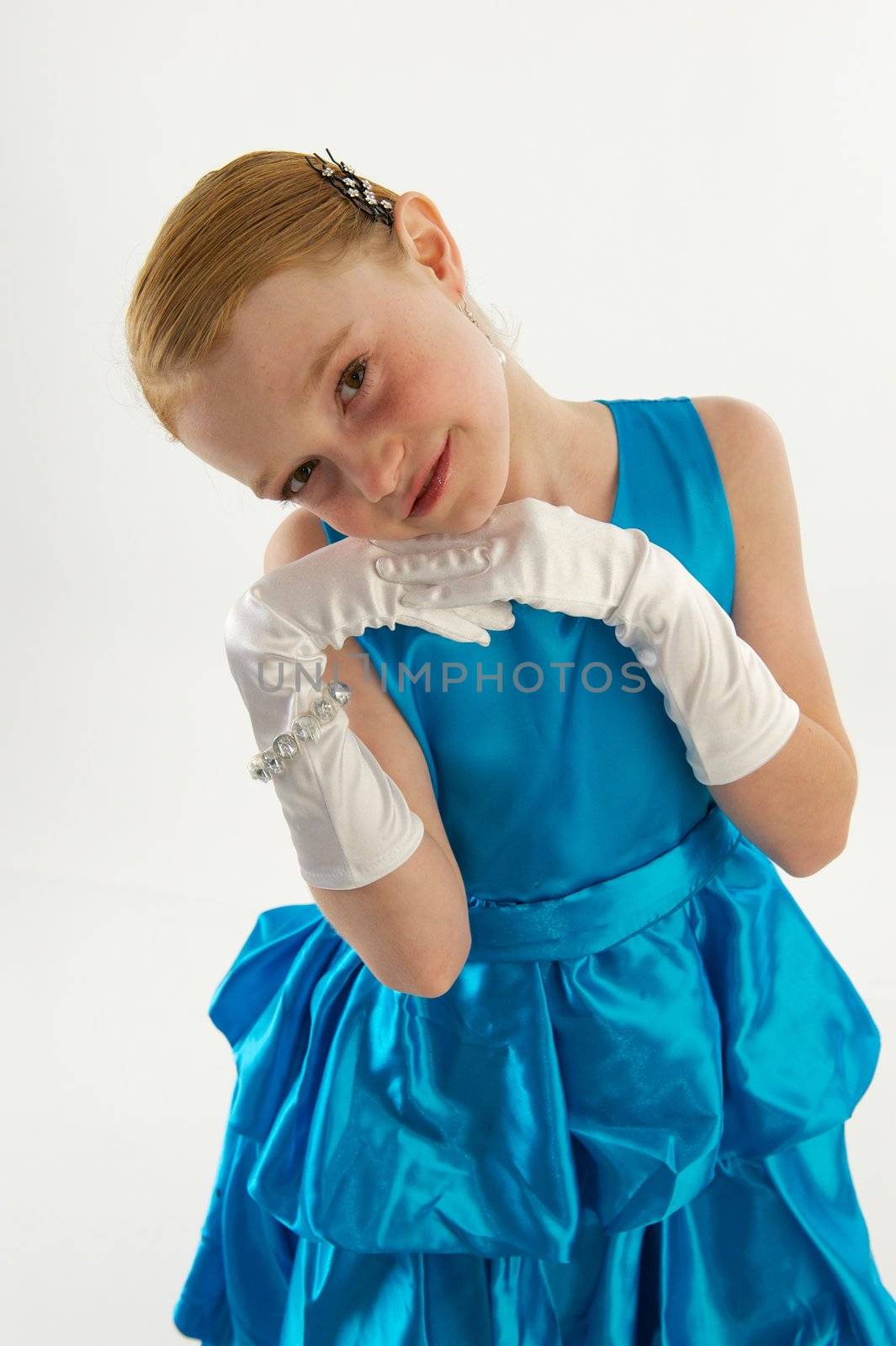 A young redheaded girl in a blue ball gown with white gloves and jewelry