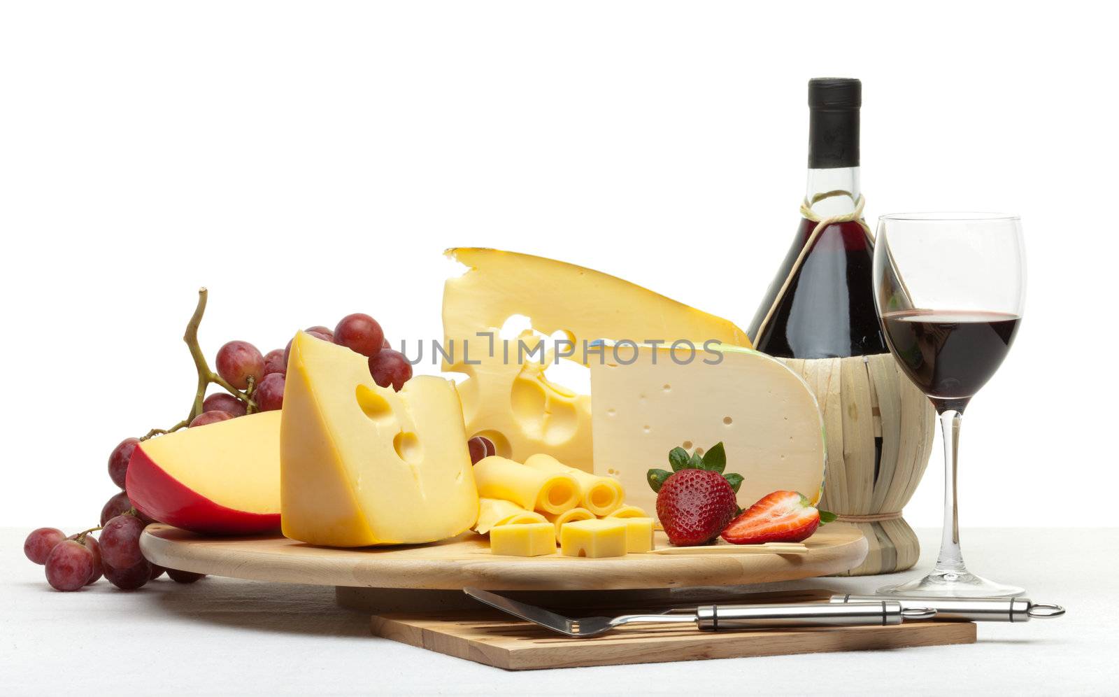 Composition of cheese, grapes, bottles and glasses of wine and strawberries on a wooden round tray on a white tablecloth, isolated on a white background
