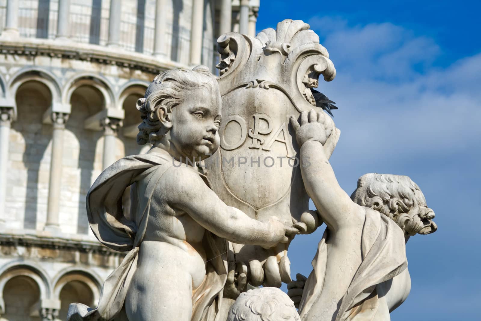 Cherub statue that sits on the Field of Miracles in Pisa Italy with the leaning tower in the background