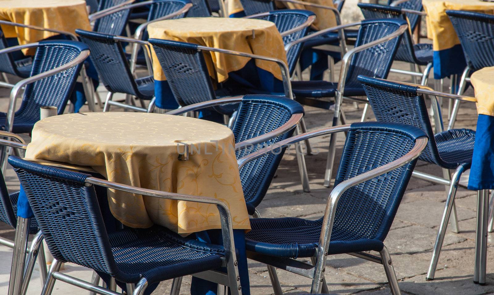 Image of a beautiful and bicolor Venetian street restaurant terrace with rattan chairs.