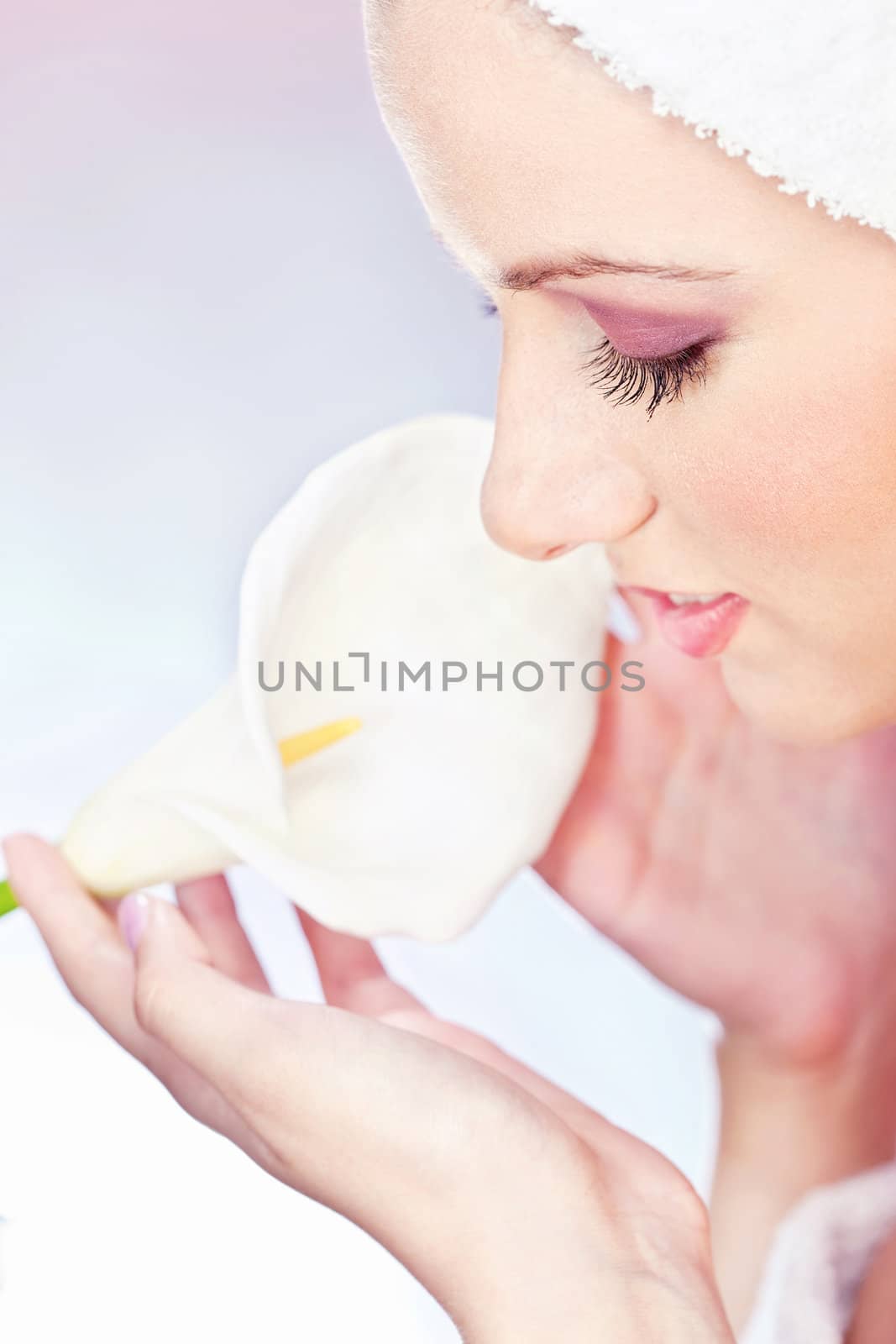 pretty woman with towel on head gently holding a white flower