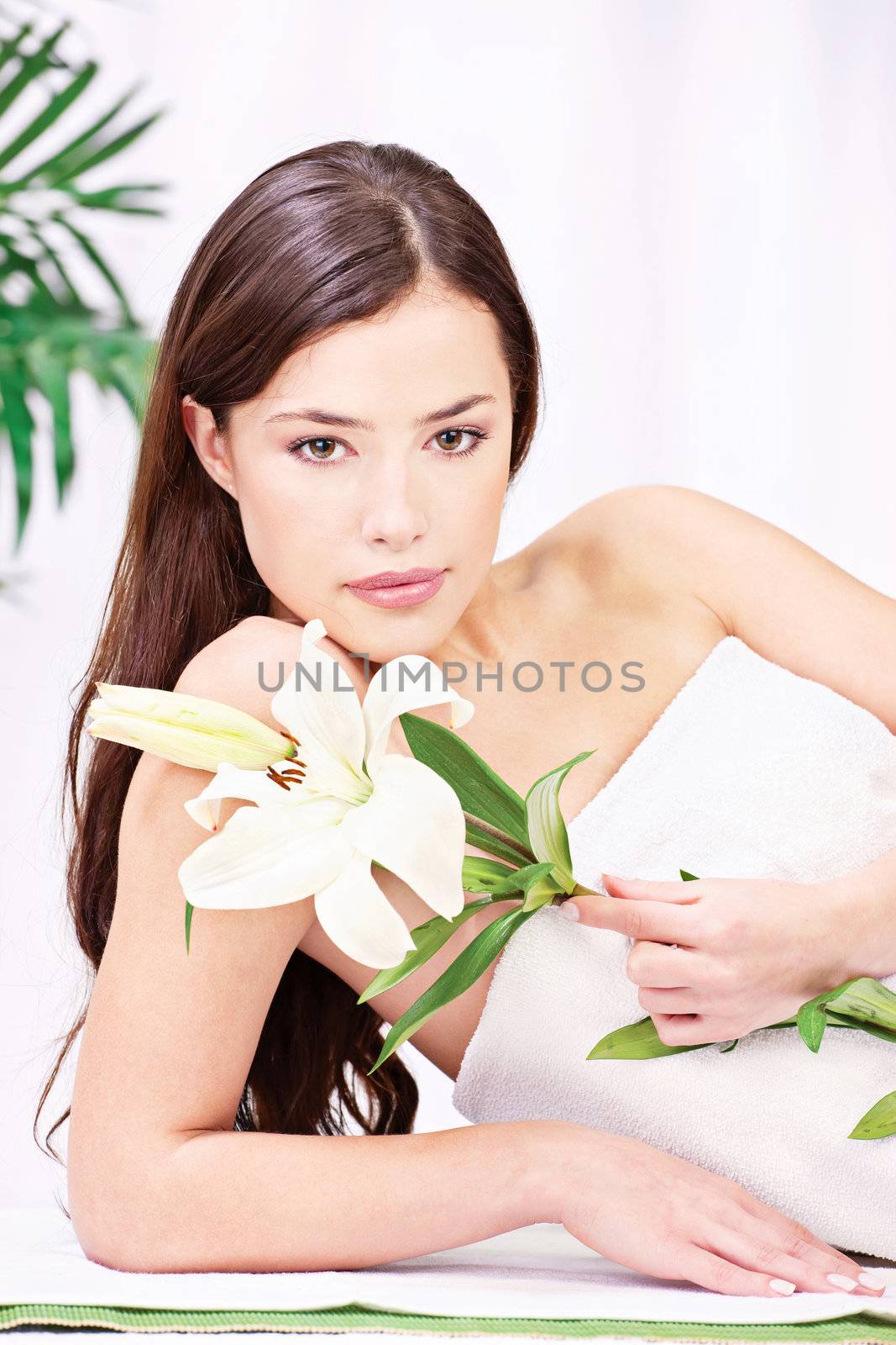 Pretty brunette woman with flower in spa salon