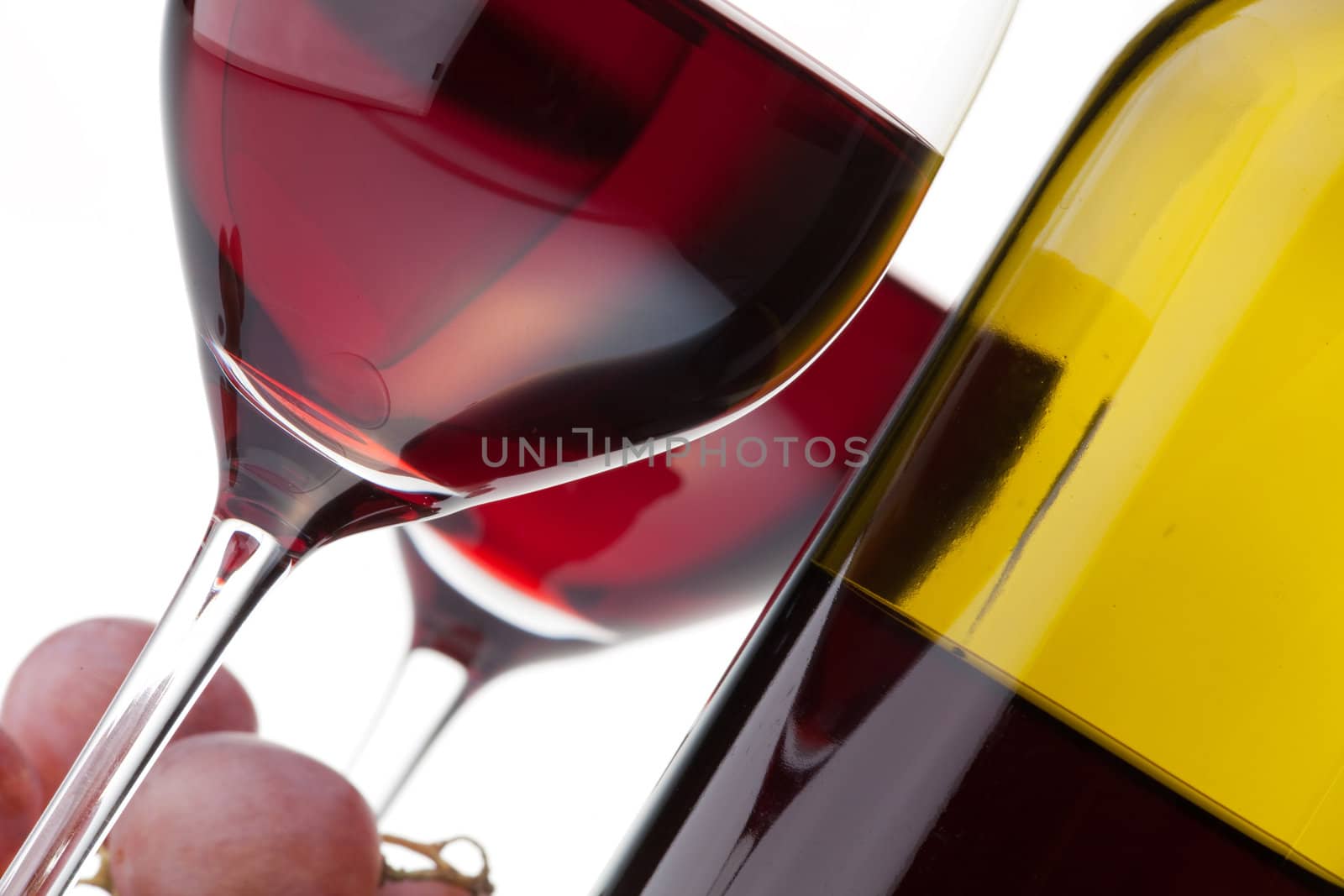 Close-up of two glasses of red wine, bottle and grapes isolated on white background