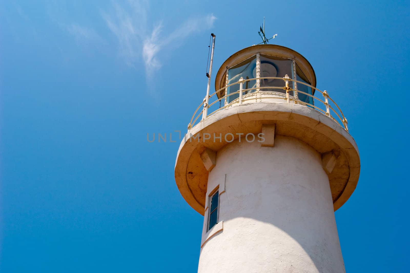 Marine white stone lighthouse in the sun against the blue sky