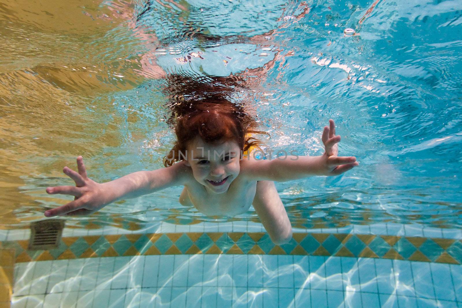 The girl smiles, swimming under water in the pool by Antartis