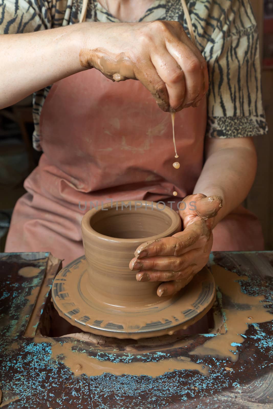 Potter creates a pitcher on a pottery wheel by Antartis