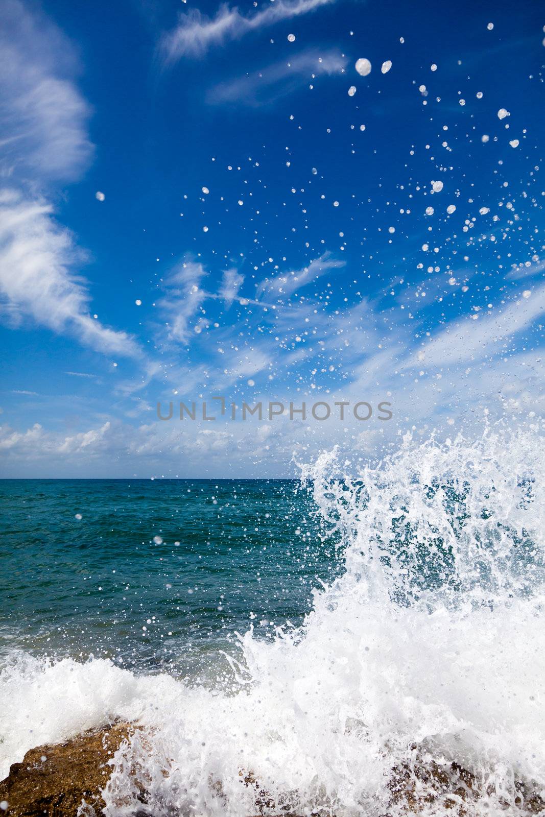 The waves breaking on a stony beach, forming a big spray