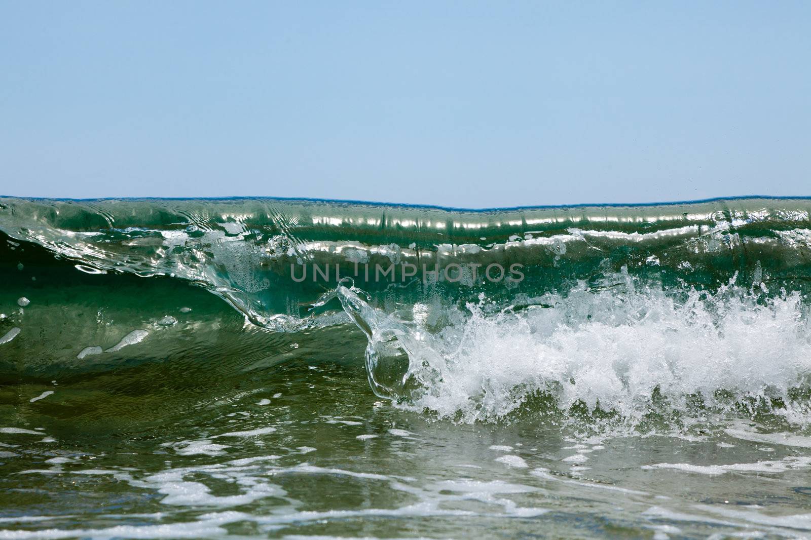 Green waves break in foam on the sea shore on a sunny day