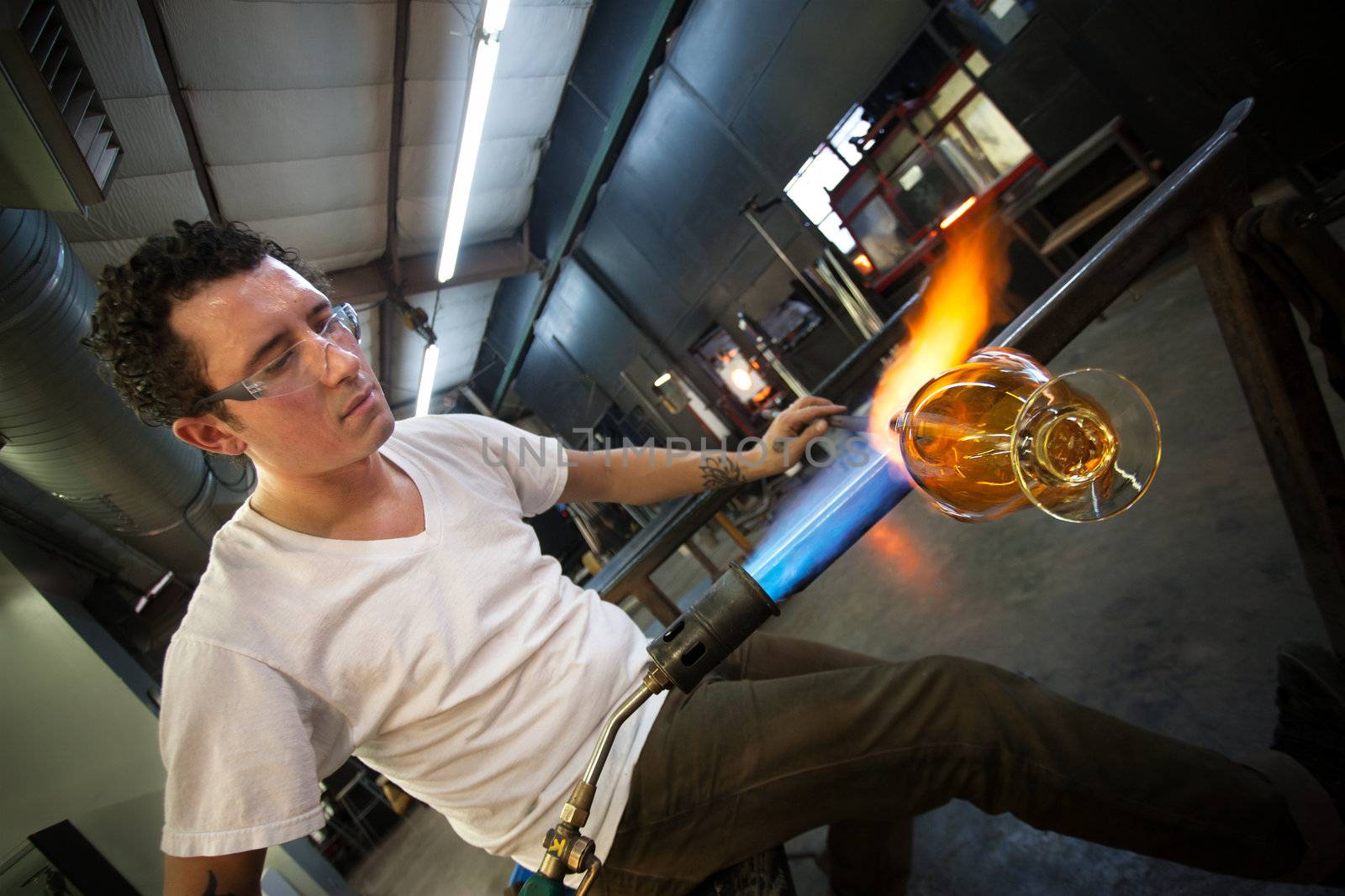 Young man working with blowtorch on glass object