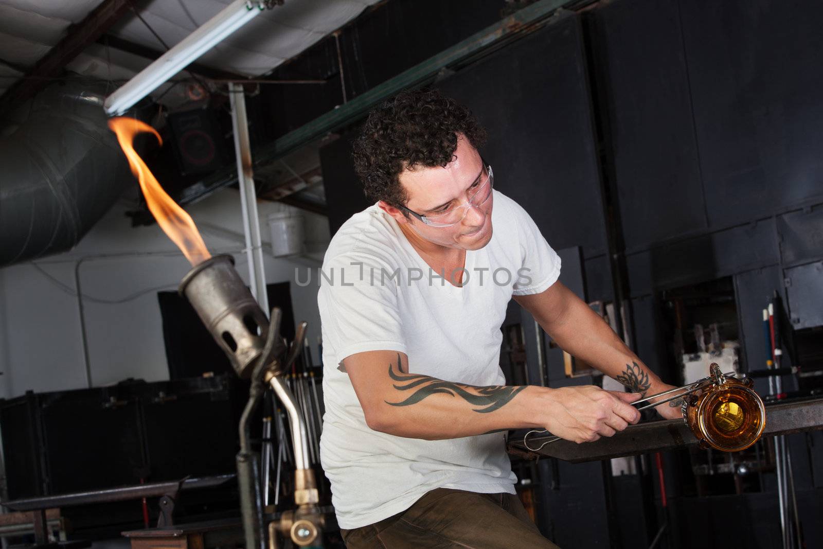 Male glass artisan with blowtorch ready nearby