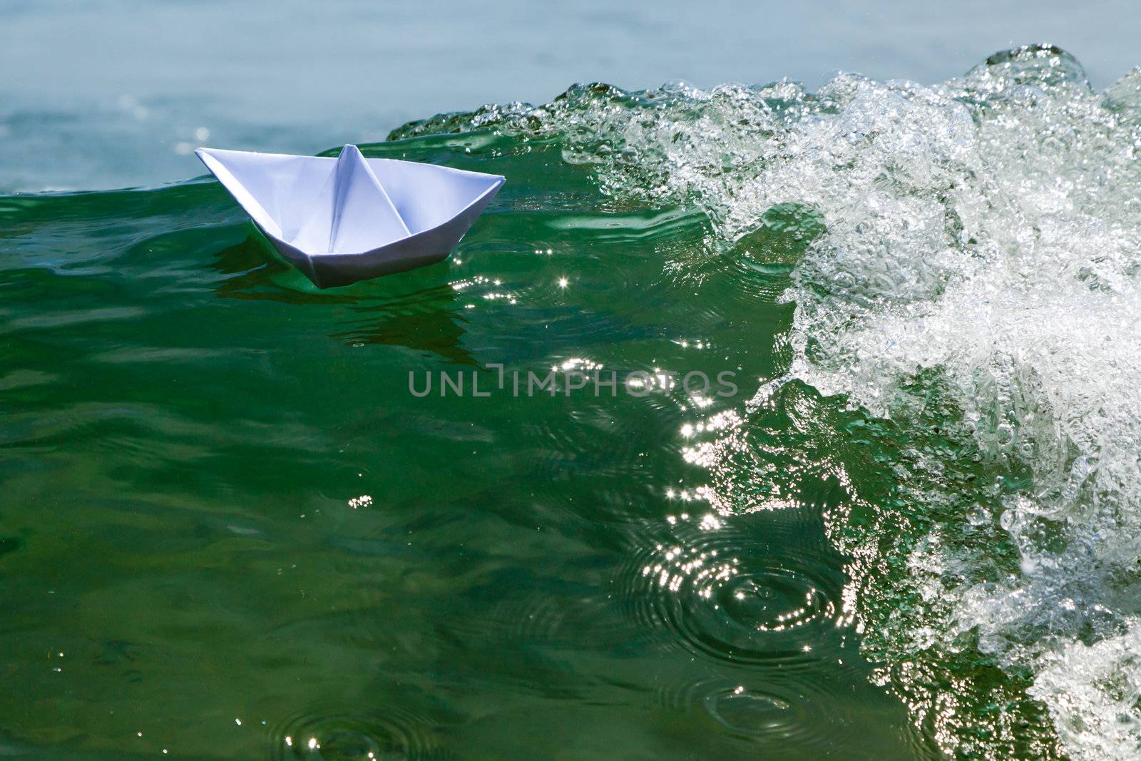 Paper boats on top of the foam of a sea wave