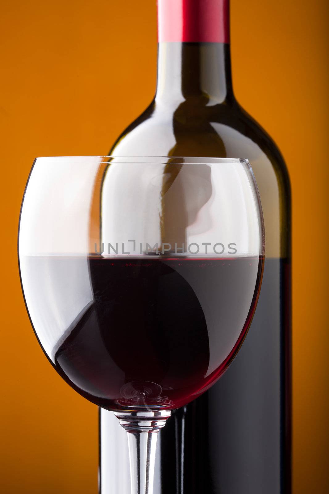 A bottle of red wine and a wine glass closeup by Antartis