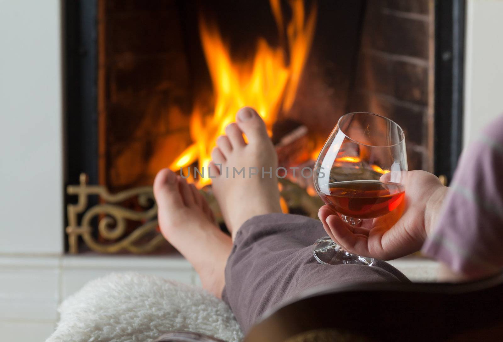 A glass of cognac on the background of a burning fireplace with a brass openwork lattice