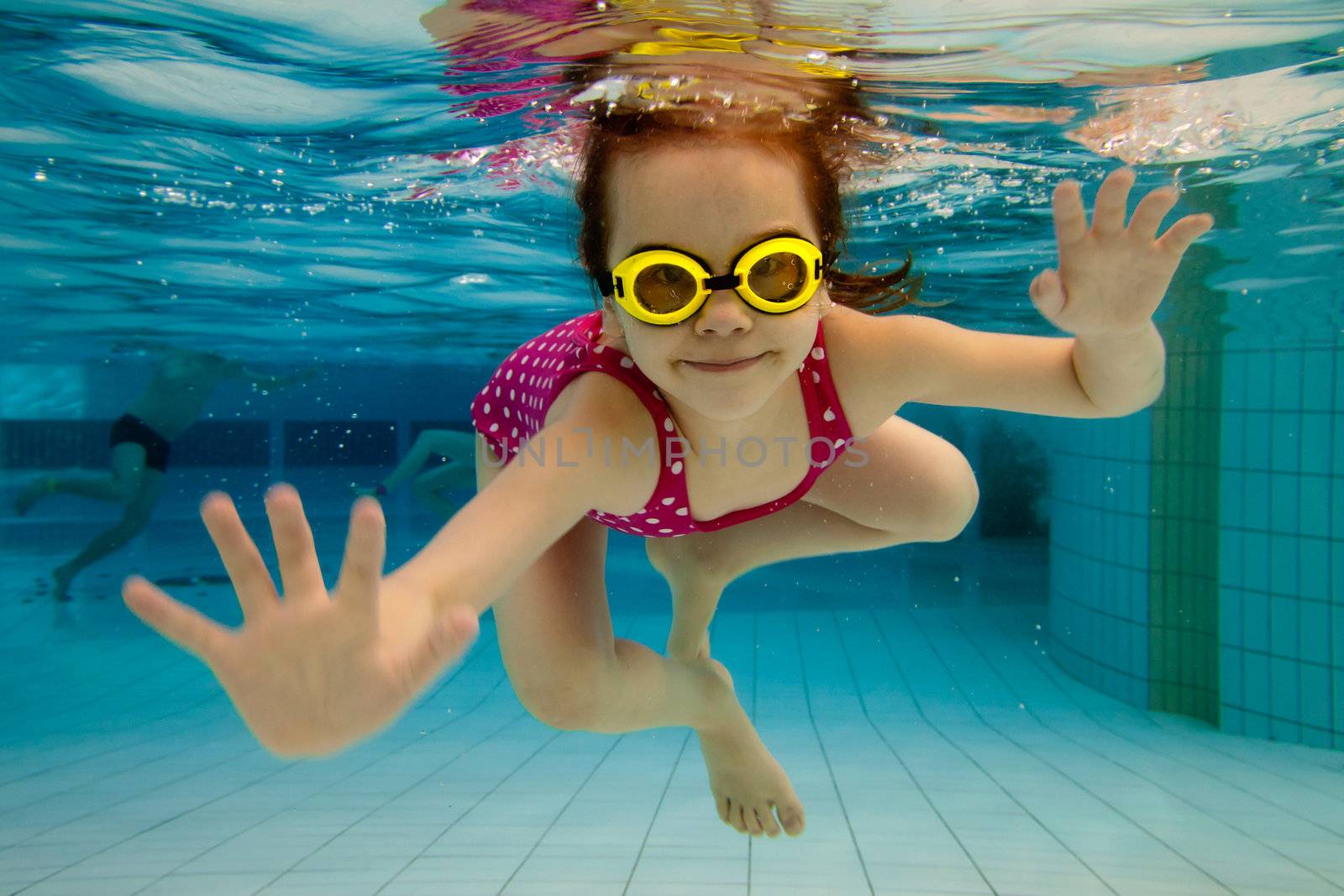 The little girl in the water park swimming underwater and smiling