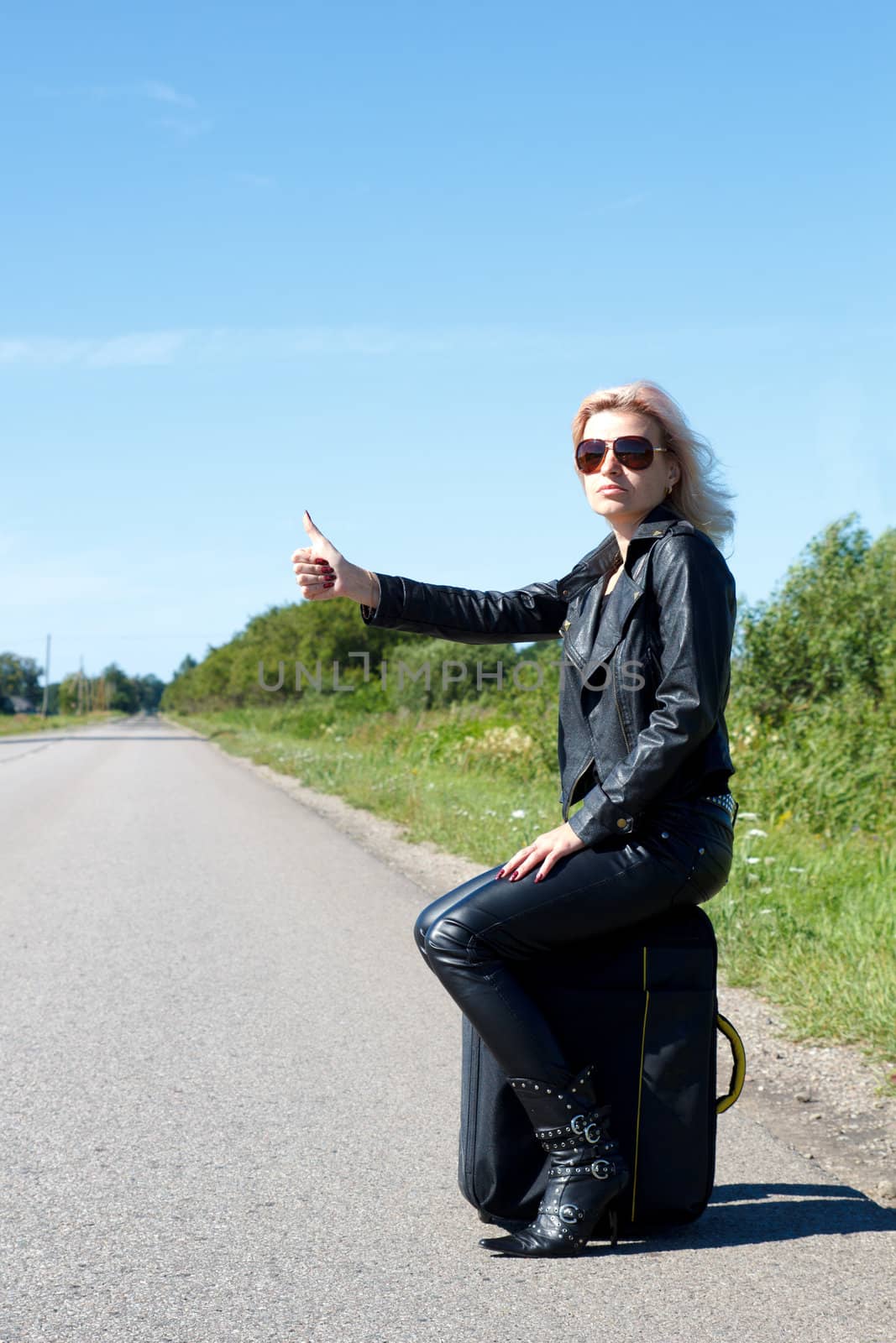 woman hitchhiking on a lonely road with her thumb up