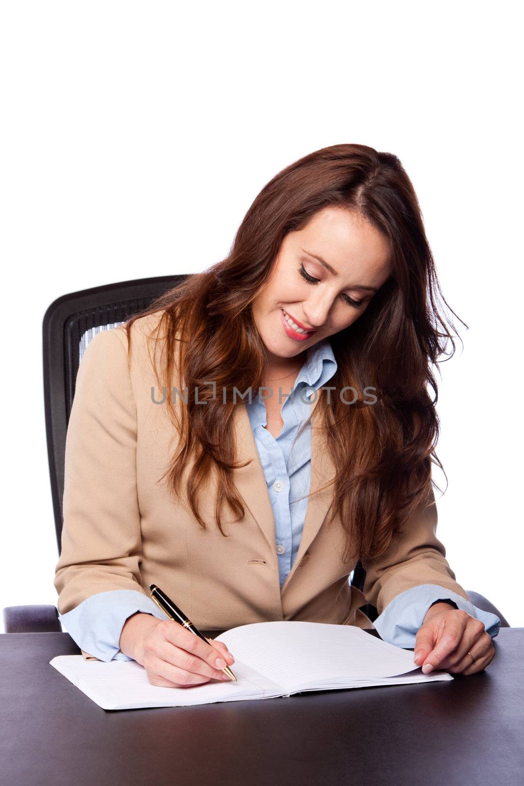 Beautiful attractive happy smiling corporate lawyer business woman sitting at desk and writing blank paper page, isolated.