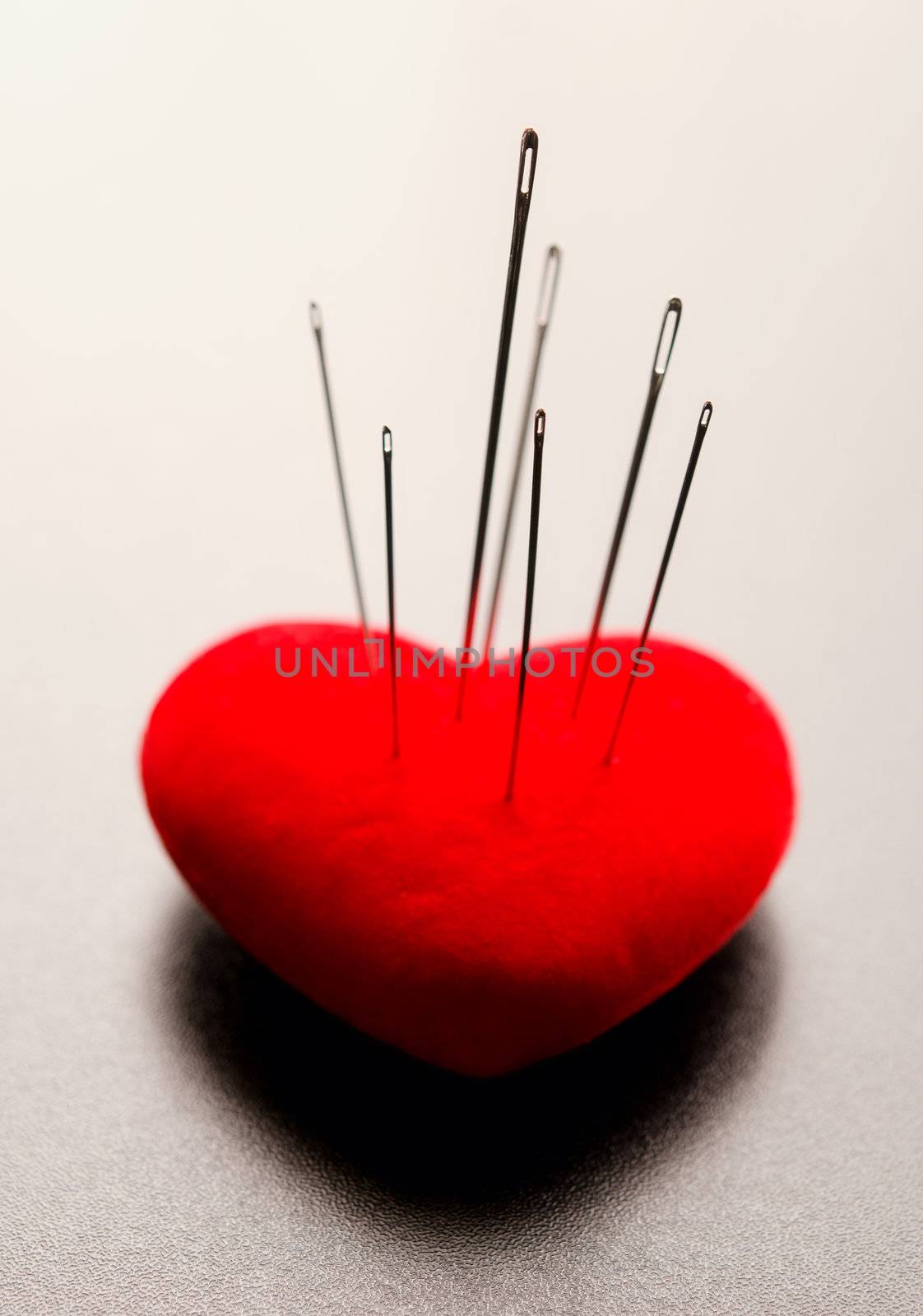 Macro shoot of a red heart Pierced by needles with selective focus on needles