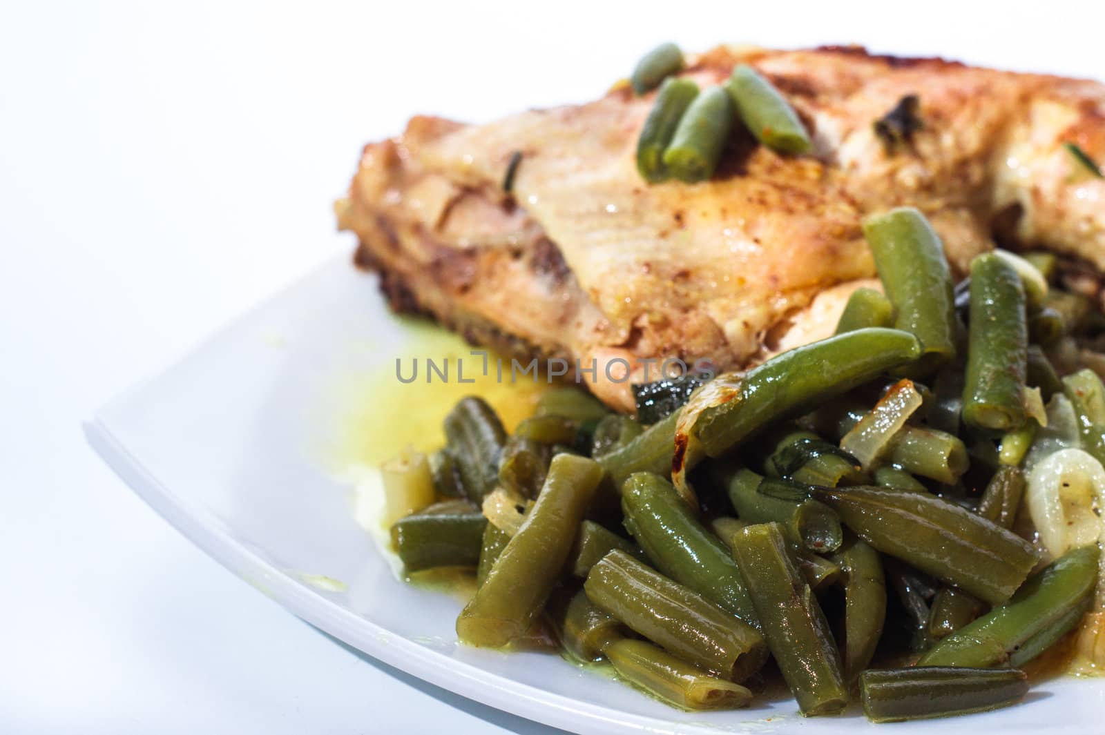 Fried chicken leg with french beans on white plate. Isolated.
