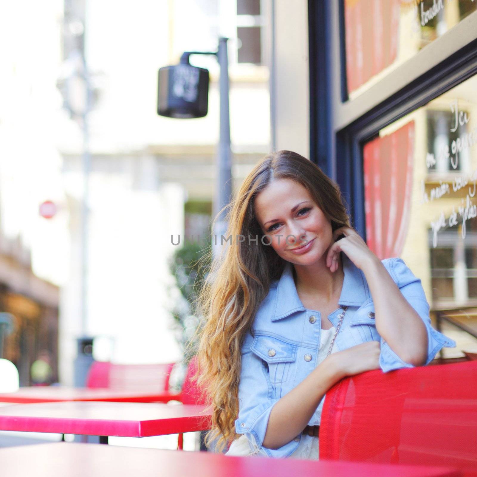 beautiful young woman sitting alone in street cafe