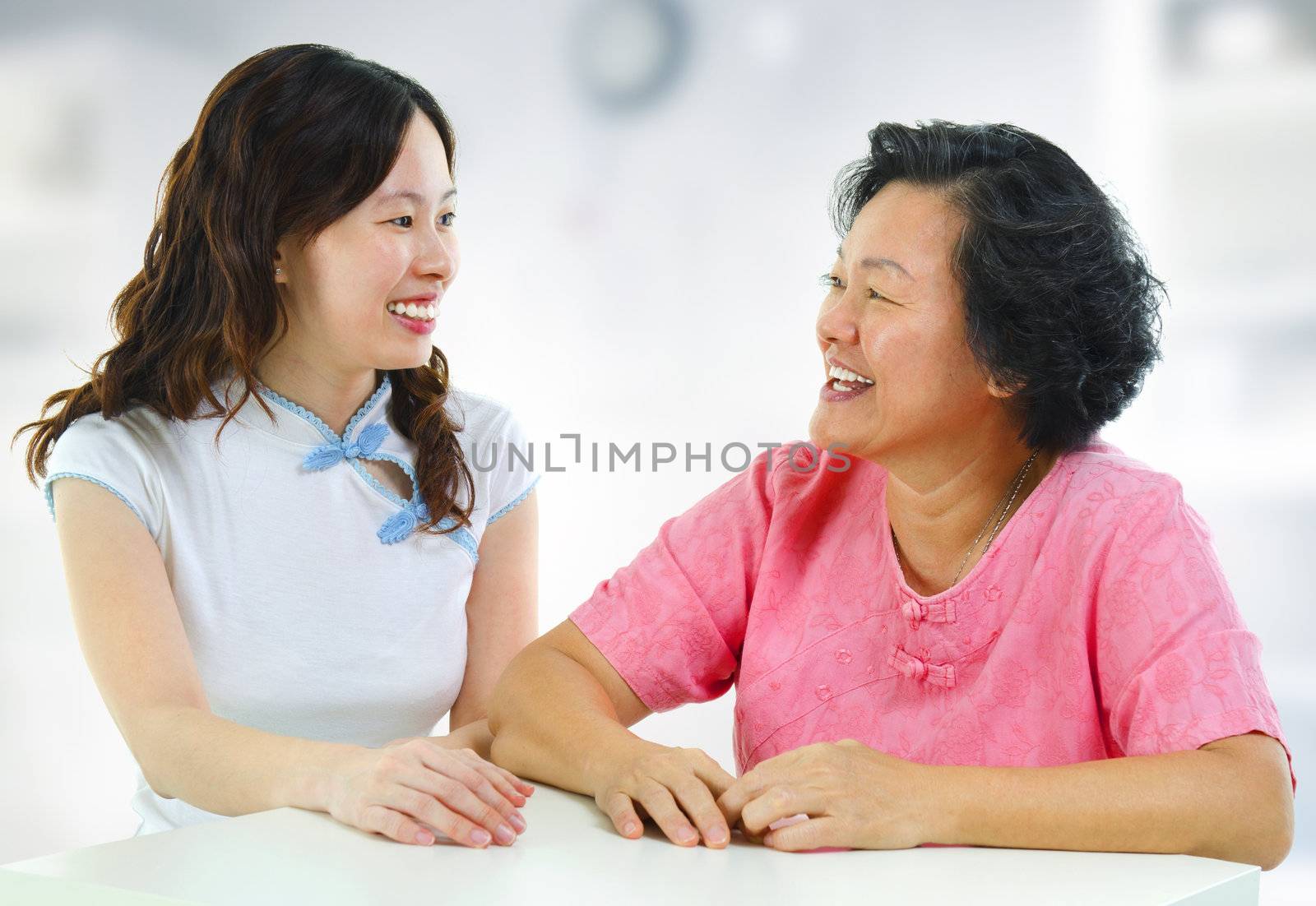 Asian family, adult daughter having conversation with senior mother indoor.