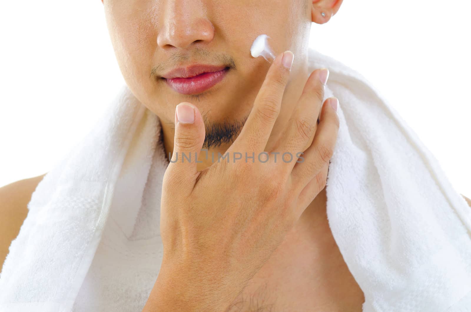Asian man putting on cream lotion on face