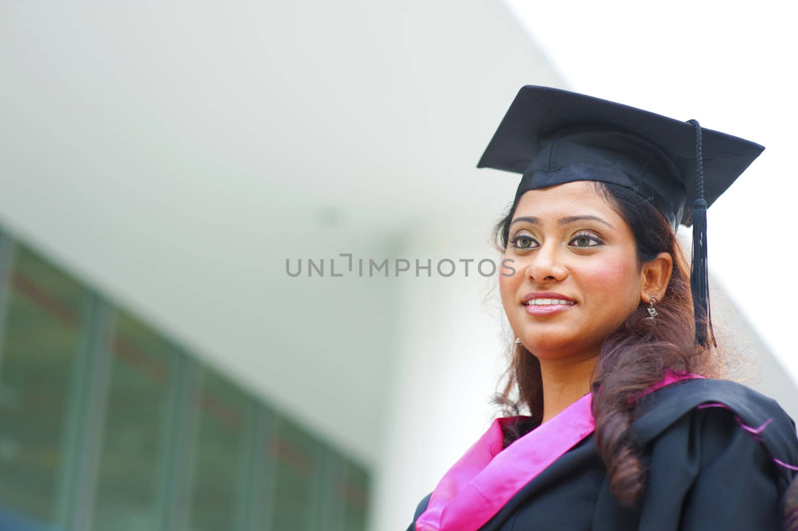 Smiling young Indian female graduate looking away