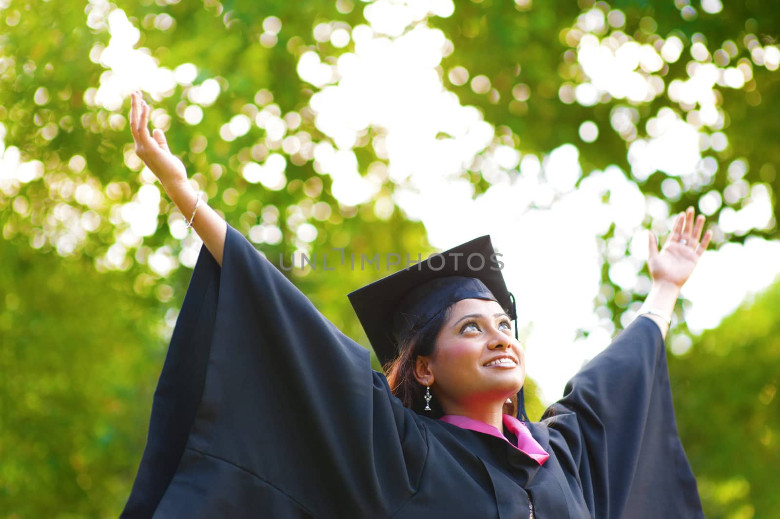 Young Asian Indian female student open arms outdoor on graduation day