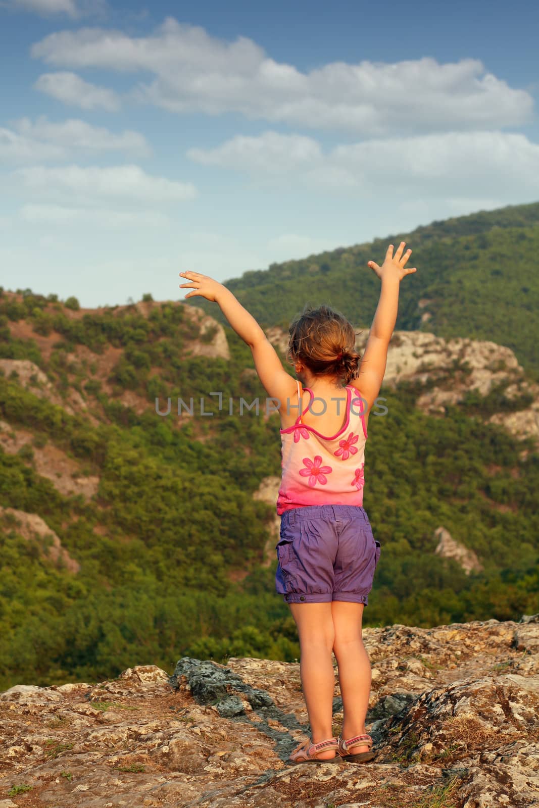 little girl standing on mountain peak