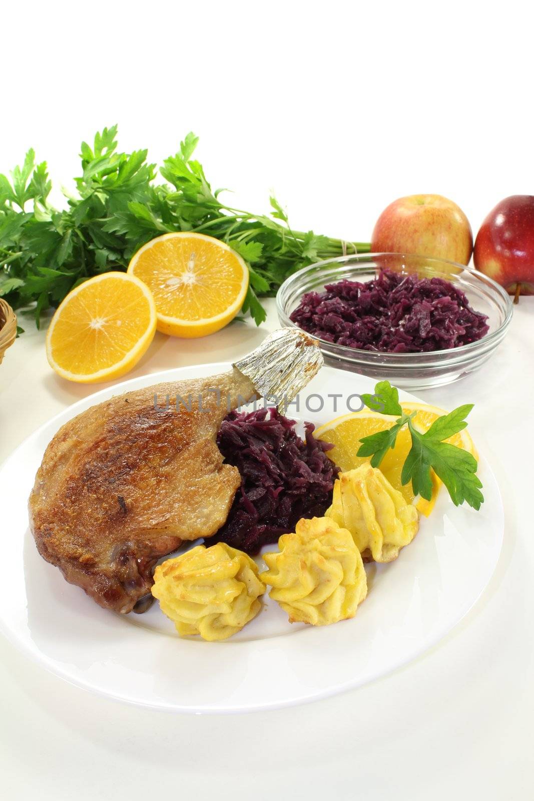 Duck drumstick with duchess potatoes and red cabbage on a light background