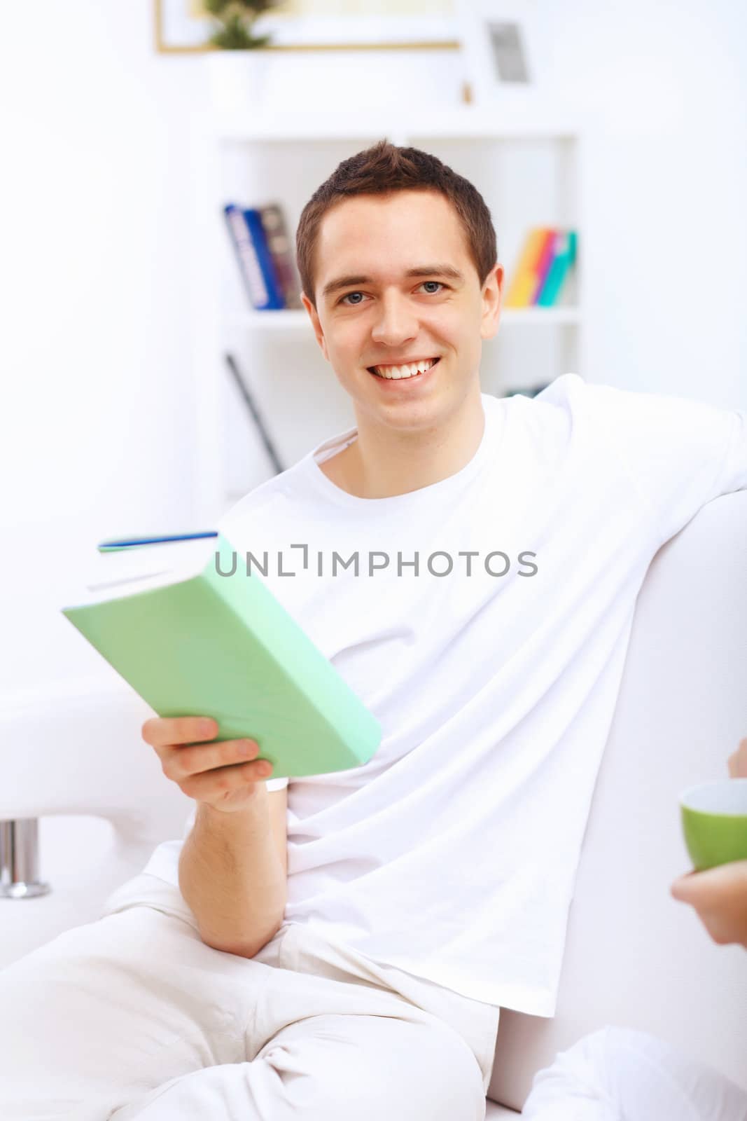 Young handsome man at home with a book