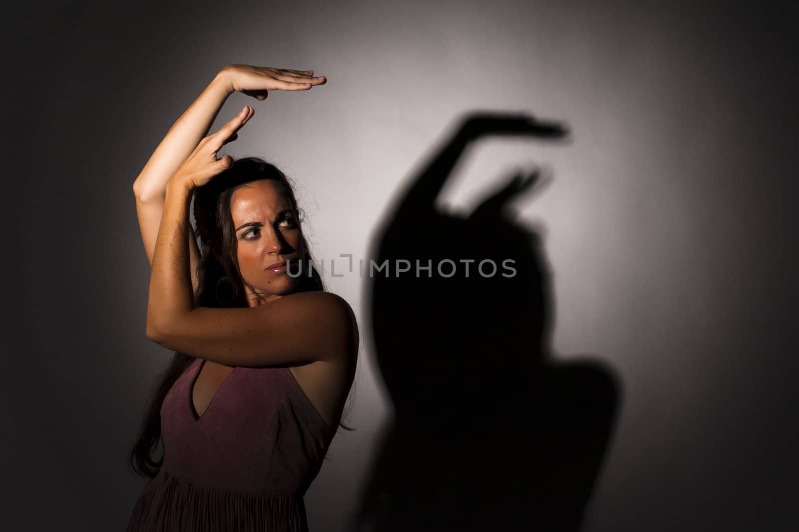 Dancer in a strong, expressive attitude with shadow on wall