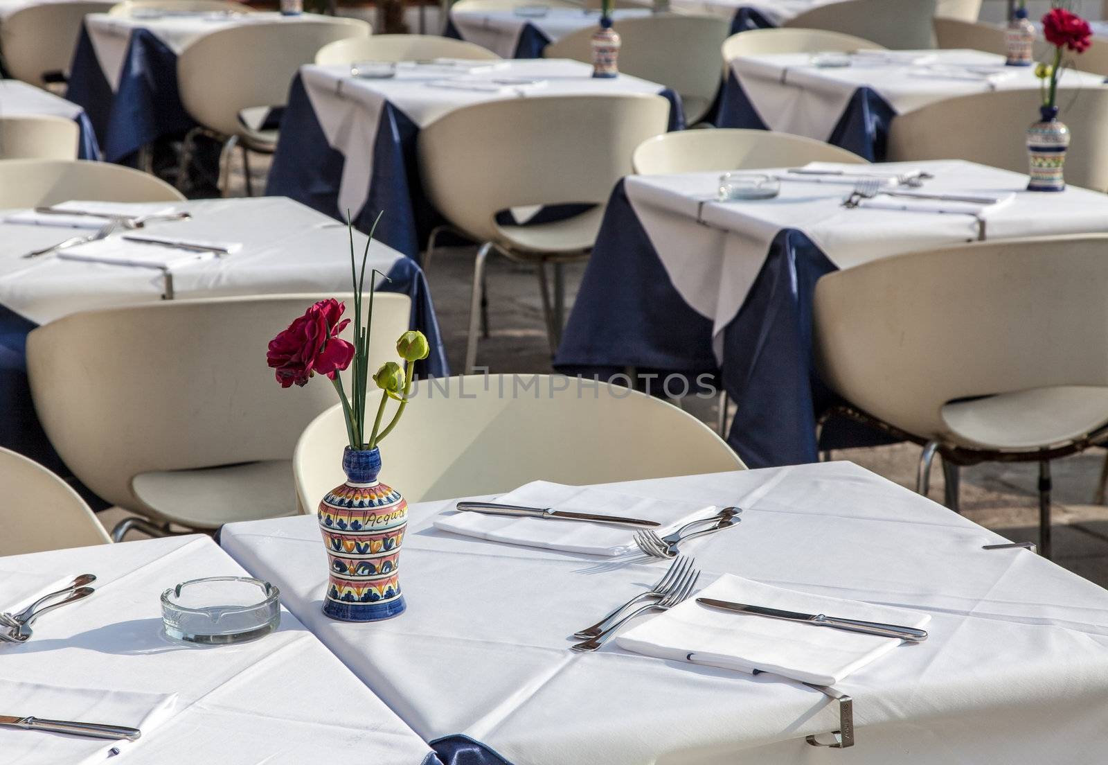 Image of a beautiful and elegant Venetian street restaurant terrace with rattan chairs.