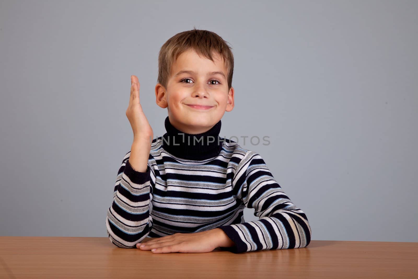 Cheerful Schoolboy ready to answer question isolated on a gray background