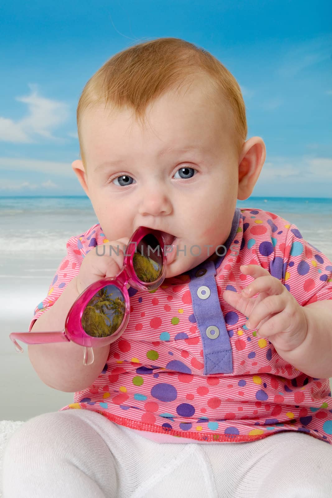 Sweet baby on vacation on beach with the sea in the background.