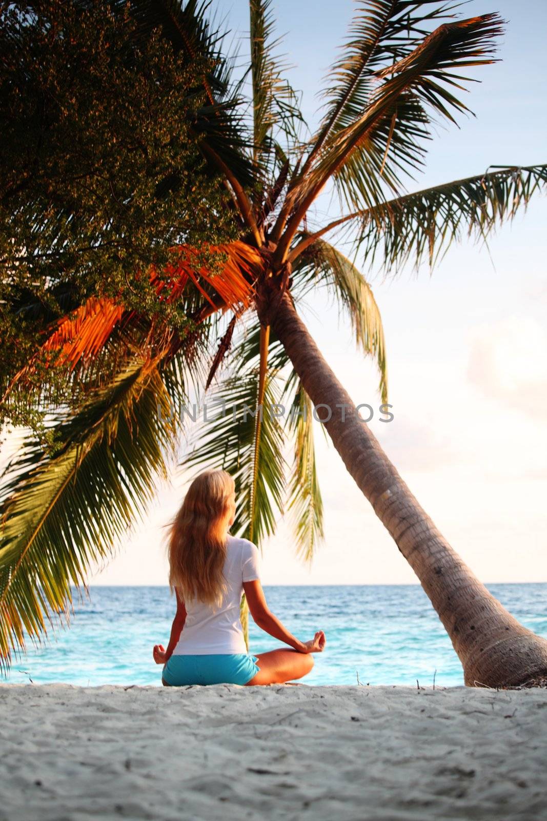 yoga woman on sea coast under palm