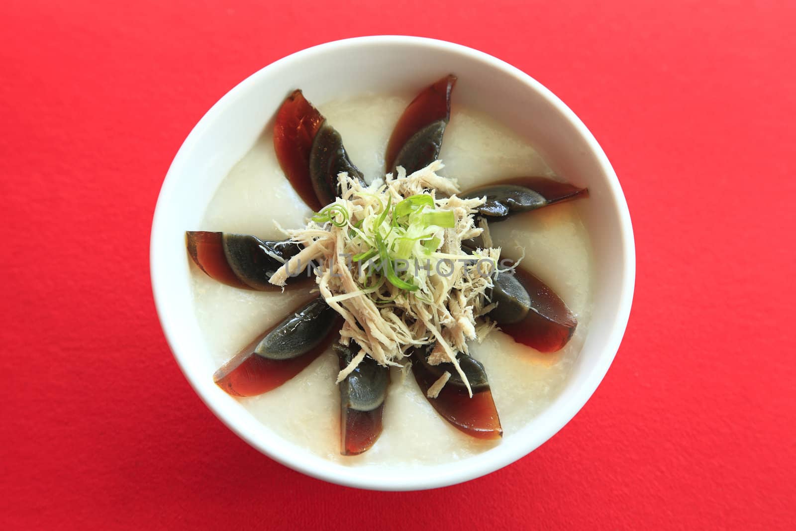 a bowl of rice porridge with chicken and potash preserved egg