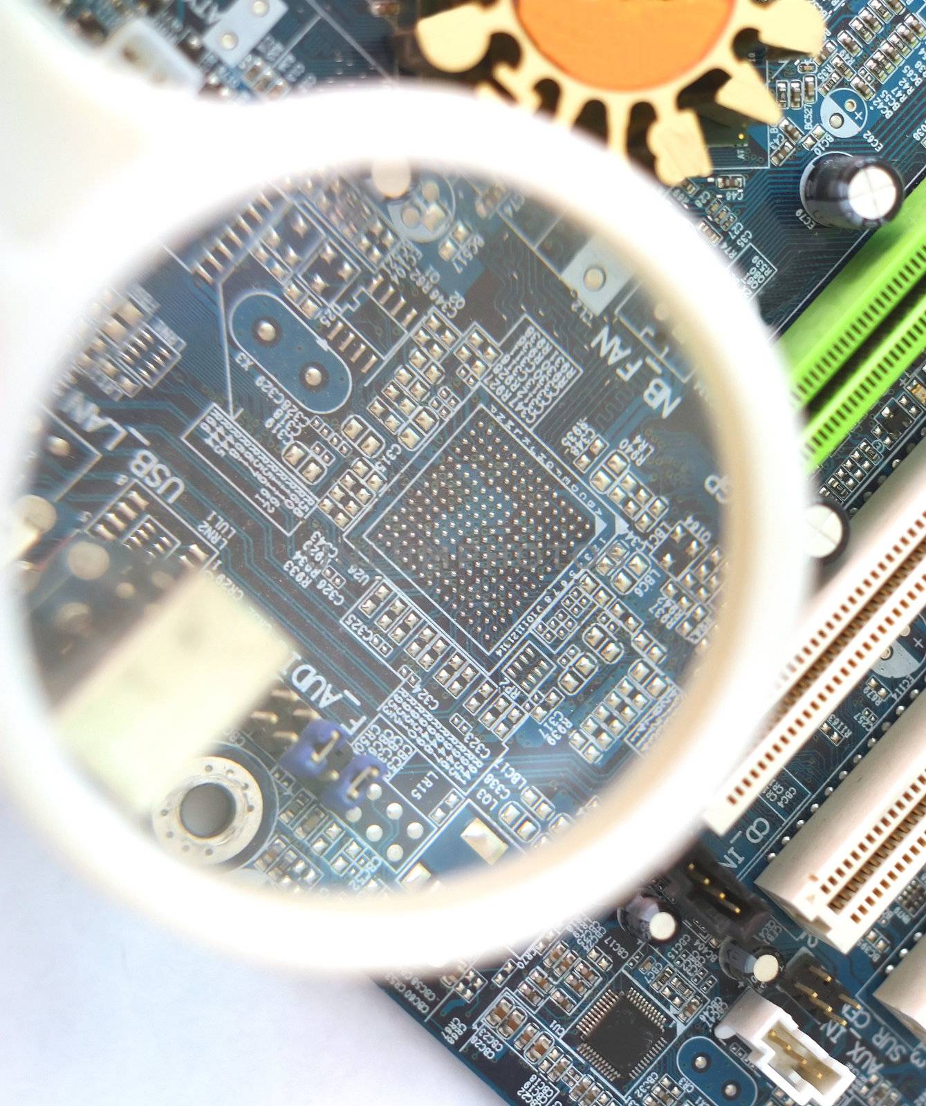 Computer mainboard under magnifying glass. Shallow DOF.