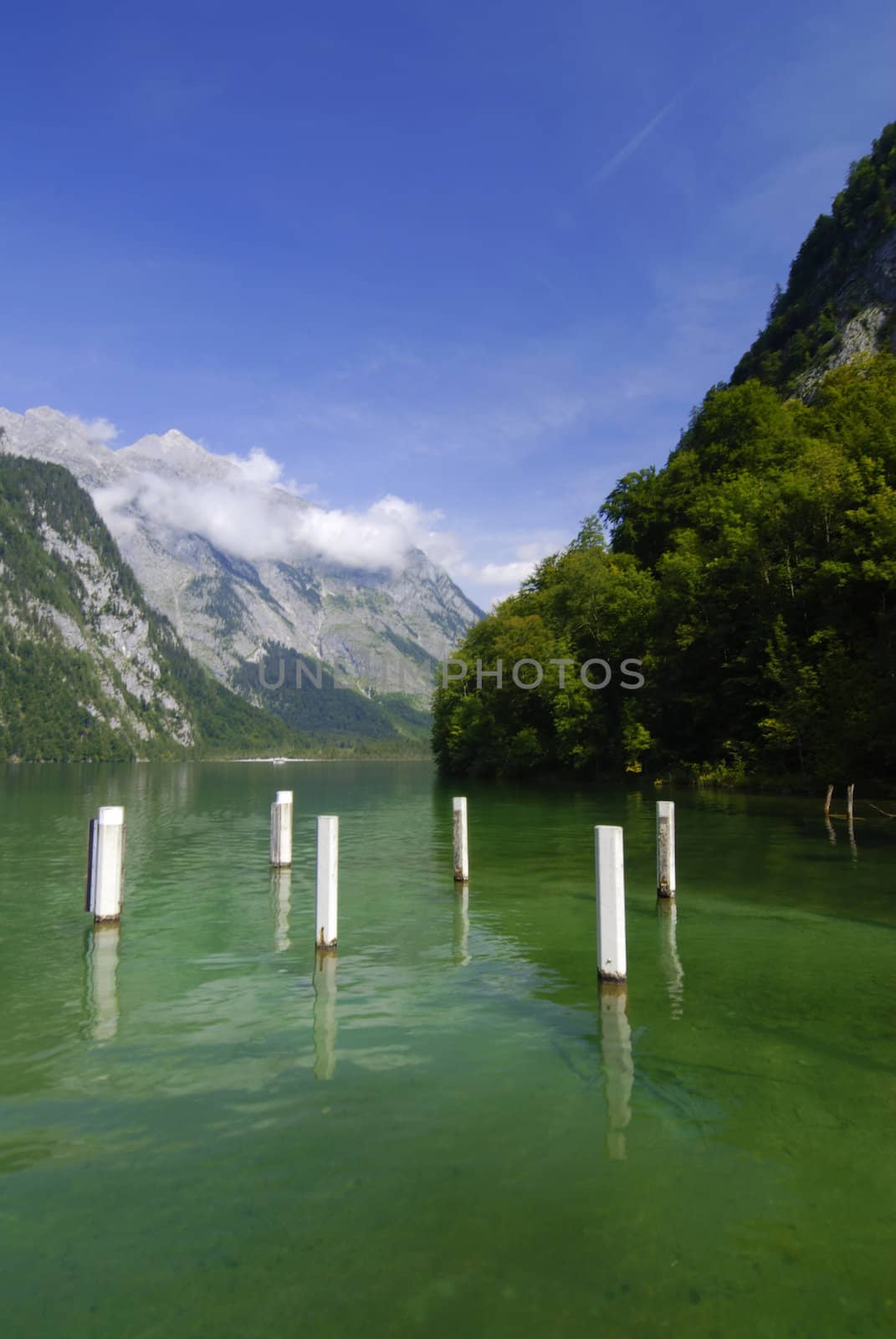 Famous lake Konigssee with boat pier and mountains with clouds