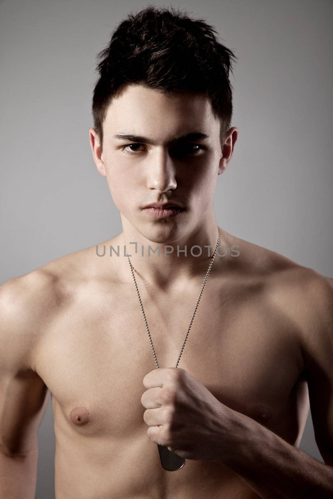 A good looking, muscular built, man on a black background with dog tags.