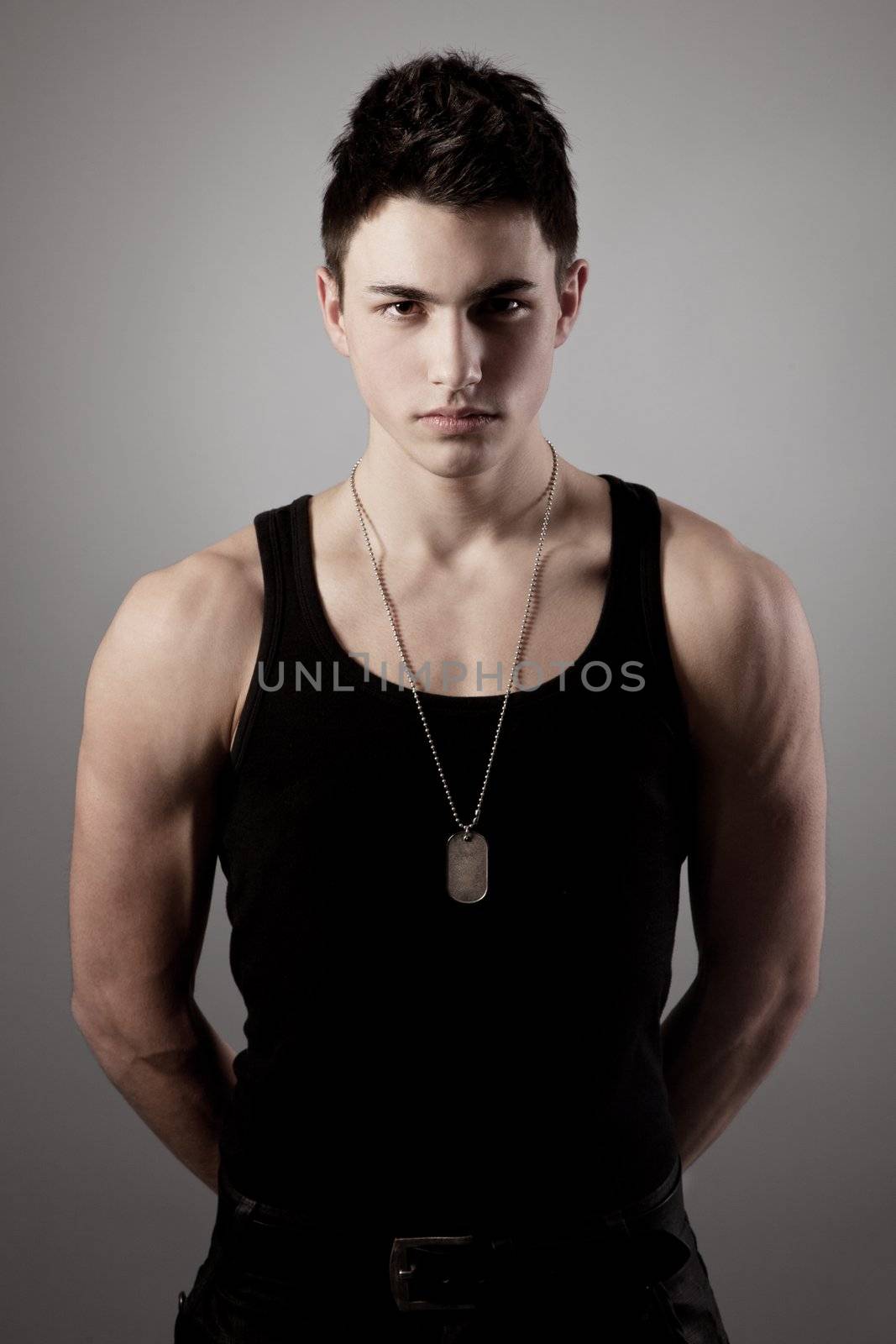 A good looking, muscular built, man on a black background with dog tags.