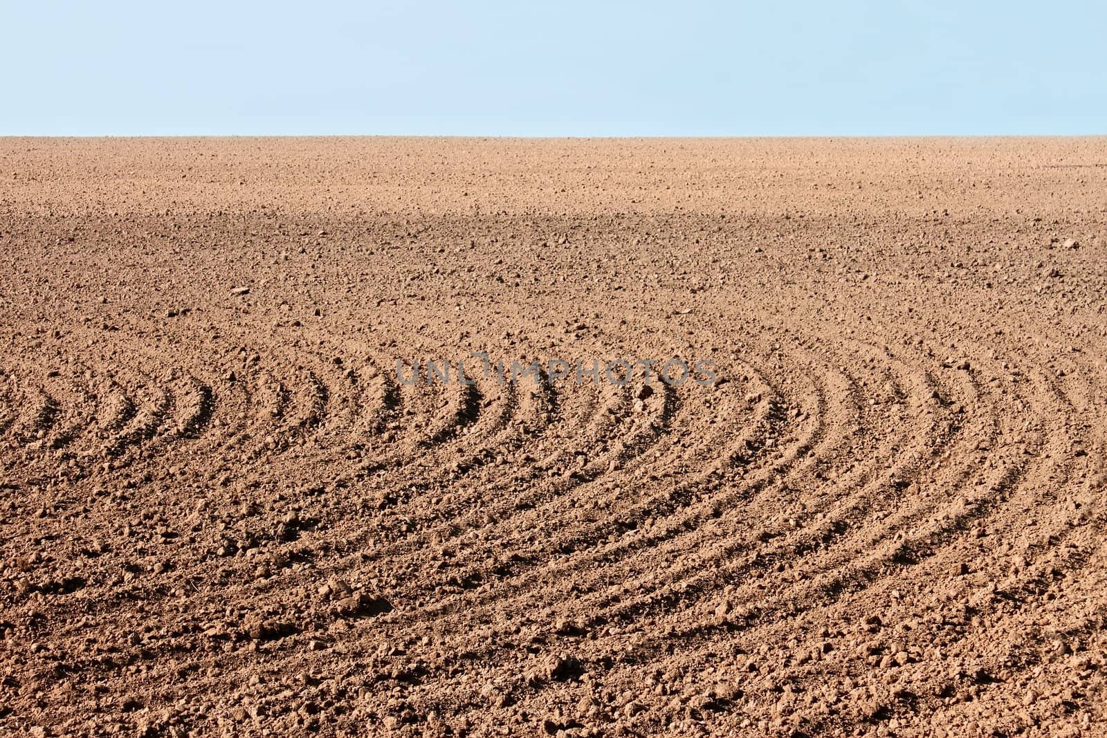 Rural landscape with parallel curved furrows on autumn field that prepared for the next season